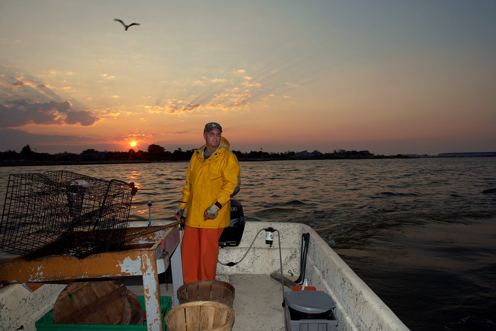 bayman in yellow slicker in boat at sunrise