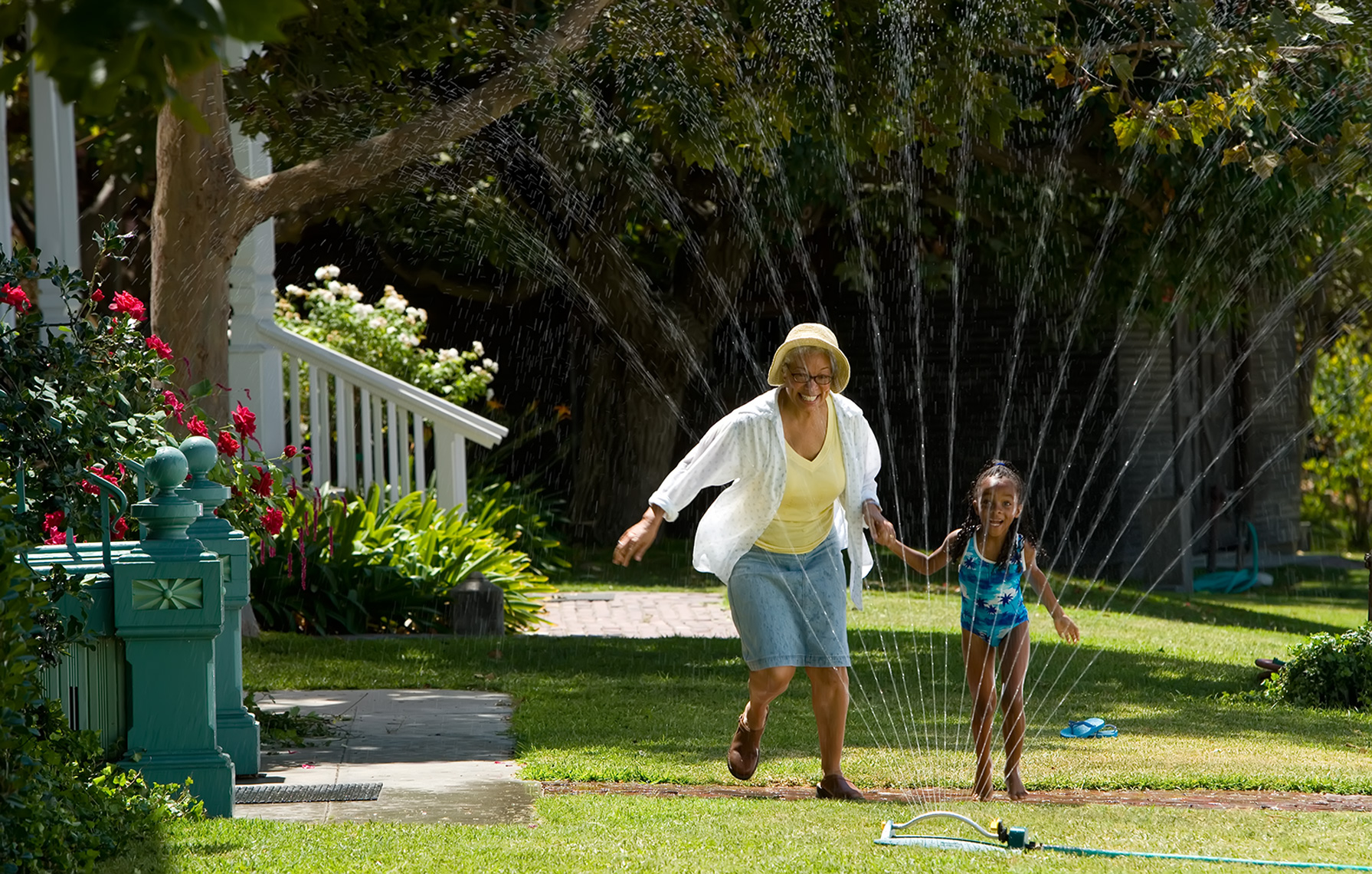 grandmother jumping through sprinkler